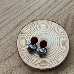 Miu Miu örhängen  - Snygga örhängen inspirerade av Miu Miu med hjärtformad detalj i silverfärg. Supersnygga och nya, köpta på marknad men inte använda. Inte äkta