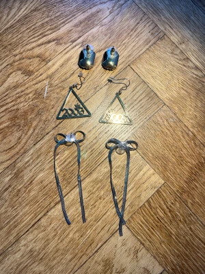 Örhängen 3 par silver  - Säljer 3 par örhängen i silver med kvadratiska svarta studdar, rosetter och en triangel med året 2006 på. Perfekt som en present eller för dig som gillar unika accessoarer! 