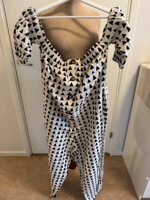 Zebramönstrad jumpsuit med bälte - Snygg kort jumpsuit med zebramönster i svart och vitt. Jumpsuit off shoulder och ett matchande bälte i midjan för en markerad siluett. Perfekt för dig som vill sticka ut med ett djurmönster och en trendig look.