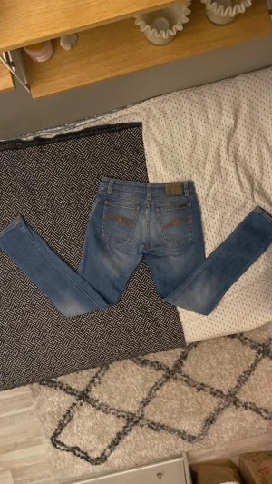 🔥 Superfeta nudie jeans gjort på denim! 🔥 - Säljer ett par snygga ljusblå skinny jeans från Nudie Jeans med klassisk femficksdesign och ljust på benen. Jeansen har hög midja och är tillverkade i 98% bomull och 2% elastan för skön stretch. Perfekt passform. 