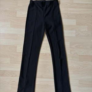 Svarta kostymbyxor från Gina Tricot stl S  - Svarta kostymbyxor från ginatricot stl S. Slits längst ner på benen.  Resår i midjan.  Använd 1 gång!