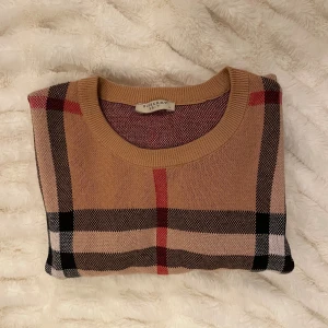 Beige rutig tröja från Burberry Brit - Snygg beige tröja från Burberry Brit med klassiskt rutigt mönster i svart, vitt och rött. Den är i mycket bra skick | Nypris  11 000kr 