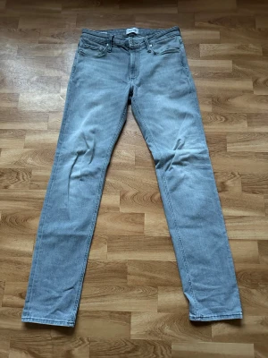 Jack & Jones Jeans - Säljer ett par Jack & Jones jeans i grått, W30/L34. Regular/Clark fit med skön passform och stilren look. Använda men i bra skick och redo för en ny ägare. Passar perfekt till både ljusa och mörka outfits.