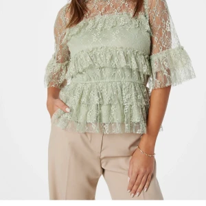 Dusty green smilla lace blouse  - Superfin dusty green blus i spets med volangdetaljer och halvtransparenta trekvartsärmar. Blusen har en feminin och romantisk look med flera lager volanger och vacker spets över hela plagget. Ordinariepris 319kr. Varan säljs inte längre. Prislappen är kvar då den aldrig använts. 
