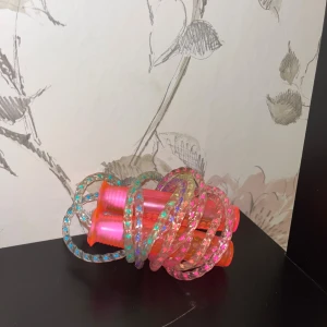 Ingen elektronikprodukt identifierad - Färgglatt hopprep med plastade handtag och glittrande rep. Produkten är i gott skick utan synligt slitage.