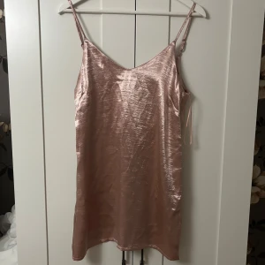 Satin pyjamas - Snygg kort slipklänning från Missguided i skimrande champagnefärgad satin. Klänningen har smala axelband, v-ringning både fram och bak samt en lösare passform. Perfekt för dig som vill ha en trendig och stilren look, eller bara vill va snygg när man sover! Aldrig använd, men när jag testat den på så va den jätteskön mot huden.