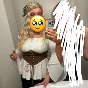 Vit offshoulder blus med brun snörkorsett - Säljer en vit offshoulder blus med vida ärmar och en brun korsett med snörning i midjan. Perfekt till halloween!!! Ex pirat🥹