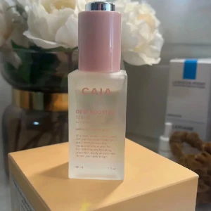 CAIA Dew Booster Serum - Dew Booster Serum från CAIA i en snygg frostad glasflaska med rosa lock och silvrig pump. Innehåller 30 ml återfuktande serum med panthenol och hyaluronsyra som ger glow och fräsch känsla till huden. Perfekt för dig som vill ha extra lyster i din hudvårdsrutin.
