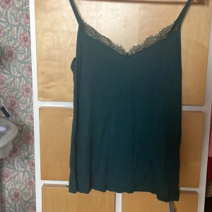 Mörkgrön linnetopp från Intimissimi L - Supersnygg mörkgrön linnetopp från Intimissimi i ultralätt material med kashmir. Topp med tunna axelband, v-ringning och spetsdetalj längs halsen. Perfekt för lager-på-lager eller som statement piece. Italiensk design, storlek L.OBS! Bara testad och pris kan diskuteras!