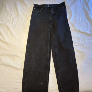Svarta raka jeans från Lindex  - Säljer ett par svarta jeans från Lindex med klassisk femficksdesign och raka ben. Jeansen har hög midja och är tillverkade i robust denim. Perfekta för dig som gillar en tidlös och clean look.