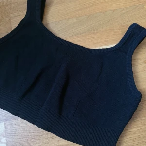 Svart stickad topp från H&M - En svart stickad topp från H&M i storlek XL. Toppen har breda axelband och ribbade kanter både upptill och nedtill. Perfekt att styla med jeans eller kjol för en enkel och snygg look.