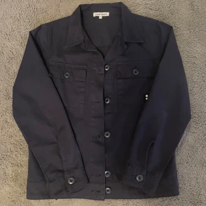Mörkblå overshirt från Cost:bart - Snygg mörkblå overshirt från Cost:bart i bomull. Jackan är i nyskick och har endast används fåtal gånger, nypris ligger på runt 700kr ‼️Storlek M vilket motsvarar 156 men jag skulle säga att den passar bra på någon runt 158-160! Hör av dig vid frågor eller extra bilder!😁