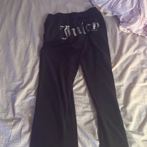 Svarta Juicy Couture mjukisbyxor - Svarta mjukisbyxor från Juicy Couture med glittrande Juicy-text baktill. Byxorna har en klassisk passform och är tillverkade i mjuk velour som känns riktigt skön mot huden. Perfekta för en chill och trendig look. Bra skick , ställ frågor om de behövs 
