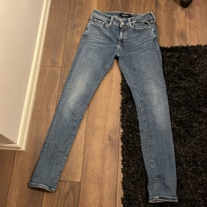 Blå skinny jeans från Replay, strl 28 - Snygga blå skinny jeans från Replay i modellen Luz. Klassisk femficksdesign, med coola detaljer på bakfickorna och dragkedja fram. Jeansen har en smal passform och är tillverkade i stretchigt denim för en bekväm känsla.