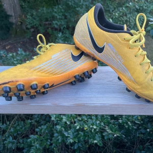 Nike Mercurial AG gula fotbollsskor - Säljer ett par gula Nike Mercurial fotbollsskor med svarta och vita detaljer. Dobbar för konstgräs, AG. 