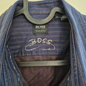 Randig blå skjorta från Hugo Boss - Jag vet inte var den är köpt, jag fick den som present för några år sedan och den passar inte längre. Lite katthår på bilderna😅