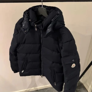 Svart Moncler dunjacka med huva - Säljer en stilren mörkblå moncler mongenevre. Storlek 2. Hör av er vid fler bilder eller eventuella frågor!🙏