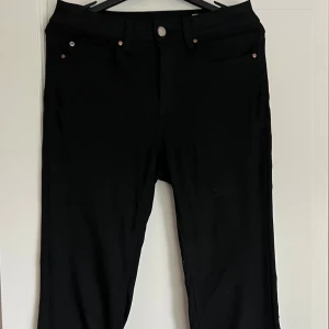 Svarta jeansbyxor i rak modell - Snygga svarta jeansbyxor med klassisk femficksdesign och raka ben. Byxorna har normal midja och är tillverkade i ett mjukt bomullsmaterial med lite stretch för extra komfort. Perfekta för dig som gillar en clean och stilren look.