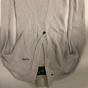 Beige stickad kofta från G-Star - Säljer en beige stickad kofta från G-Star i storlek M. Koftan har ribbad struktur, långa ärmar och knäppning framtill med två knappar. Broderad G-Star-logga på ena sidan. Perfekt för lager-på-lager och chill stil.