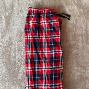 Röd-rutiga mjukisbyxor - Riktigt sköna mjukisbyxor i röd, blå och vit rutig design. Byxorna har resår i midjan och snörning med mörkblå band. Perfekta för chill dagar hemma. Tillverkade i mjukt bomullstyg. Byxorna kommer passa för dig som är mellan 160-162