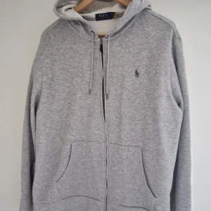 Grå hoodie från Polo Ralph Lauren - Grå hoodie från Ralph Laure. Lite liten i storleken, jag är 190 lång och har växt ut den. Så passar nog bättre som en M. Bara andvänd ett handfull gånger då den som sagt är för liten.
