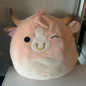 Squishmallows Howland - Supermjuk och stor Squishmallows Howland, original med tagg. Fint skick utan synligt slitage, perfekt som kramdjur eller dekor. Söt design med horn och ring i nosen, tillverkad 2023. Passar både barn och vuxna som älskar mjuka gosedjur 