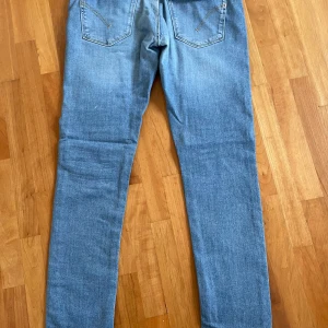 Ljusblå jeans från Dondup Limited Edition - Snygga ljusblå jeans från Dondup Limited Edition, tillverkade i Italien. Jeansen har klassisk femficksdesign, raka ben och subtila slitningar framtill. Materialet är mjukt denim med guldfärgade sömmar och silverfärgad knapp med logga.