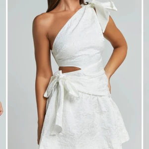 Vit oneshoulder kortklänning med rosett - Superfin vit kortklänning i oneshoulder-modell med stor rosett på axeln och knyt i midjan. Klänningen har lätt struktur i tyget och en liten cut-out vid midjan. Beställde som studentklänning men är tyvärr lite liten, helt ny med lapp och förpackning kvar, endast testad!!