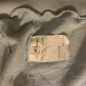 Dolce & Gabbana boxningströja ljusgrå - Ljusgrå tröja från Dolce & Gabbana med boxningsinspirerat tryck i rött, svart och brunt framtill. Tröjan har ribbad krage, muddar och nederkant samt två snedställda fickor med dragkedja. Tillverkad i bomull och har hel dragkedja framtill.