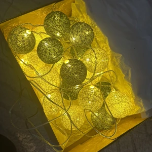 Ljusslinga med bollar, LED - Dekorativ ljusslinga med bollar i olika färger, LED-belysning och nätadapter. Perfekt för mysig stämning i hemmet. Fungerar utmärkt, inga synliga defekter eller slitage. Två färgvarianter: gul/grön och blå/grå. Säljes komplett med adapter.