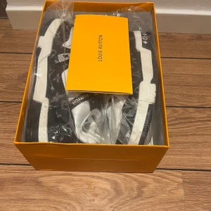 Louis Vuitton monogram sneakers svart/vit - Snygga Louis Vuitton sneakers i svart och vitt med klassiskt monogrammönster. Skorna har vit ovandel i skinn och svarta detaljer i textil med LV-logga, samt vit sula och snörning. Perfekta för dig som vill sticka ut med lyxig streetstyle. Priset kan sänkas