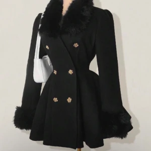 Svart kappa med fuskpäls och guldknappar - Stilren svart kappa med markerad midja, bred krage och ärmslut i fuskpäls. Dubbelknäppt framtill med dekorativa guldknappar. Jackan har en elegant, utsvängd siluett och långa ärmar. 