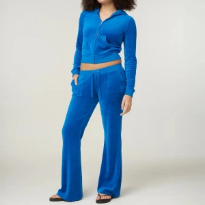 Juicy Couture set - Säljer ett set från Juicy Couture med byxor med  breda ben och snörning i midjan. Baktill finns glittrande Juicy-text i strass. Byxorna är tillverkade i mjuk velour och har en avslappnad passform med fickor framtill. Dessutom en matchande hoodie. Hoodie storlek: S, Byxor storlek: XS. Hela setet kan köpas för 700 kr, vill man köpa separat så blir det 400 kr/del. Skriv för egna bilder.