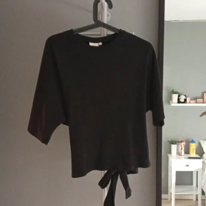 Svart knyt-topp från Nelly - Svart topp från Nelly med korta ärmar och rund halsringning. Med knyte på ryggen. Pris kan diskuteras