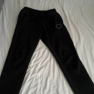 Svarta mjukisbyxor från Hugo Boss - Svarta mjukisbyxor från Hugo Boss med elastisk midja och snörning. Byxorna har fickor på sidorna och en snygg Boss-logga tryckt i vitt på ena benet. Perfekta för chill eller träning, riktigt sköna och stilrena.