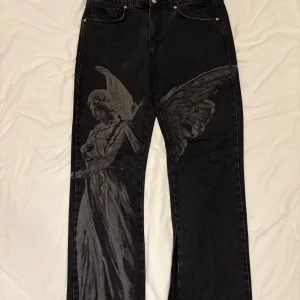 Svarta jeans med ängeltryck Reputation Studios - Unika svarta jeans från Reputation Studios med stort grått ängeltryck på ena benet. Detta är flared jeans så det passar folk med olika längder. Pris kan diskuteras då jag försöker bli av med så mycket som möjligt.