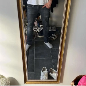 Mörkgrå dondup jeans med slitningar - Säljer ett par mörkgrå dondup jeans med snygga slitningar och tvättade detaljer. Jeansen har klassisk femficksdesign.