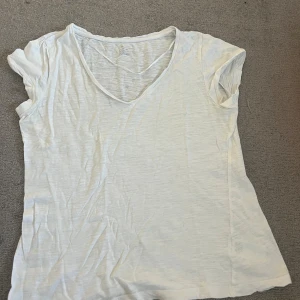 Vit v-ringad t-shirt i bomull - Enkel och stilren vit t-shirt med v-ringning och korta ärmar. Tillverkad i tunn, lätt och mjuk bomull som känns skön mot huden. Perfekt för varma dagar och enkel att matcha med allt och är lite genomskinlig.