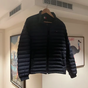 Mörkblå dunjacka från Tommy Hilfiger - Snygg mörkblå dunjacka från Tommy Hilfiger med klassisk quiltad design. Jackan är i bra skick men inga defekter. De. Har down feather vilket ger extra mycket värme. Perfekt nu till hösten när de är lite kyligt ute. Nypris 1800