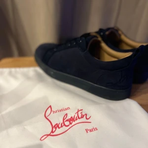 Mörkblå sneakers från Christian Louboutin - Snygga mörkblå sneakers från Christian Louboutin med rund tå och platt sula. Skorna är tillverkade i mjuk mocka och har snörning framtill. På hälen finns broderad Louboutin-logga i matchande färg. Insidan är beige och ger en lyxig känsla.  Vet ej om dem är äkta!