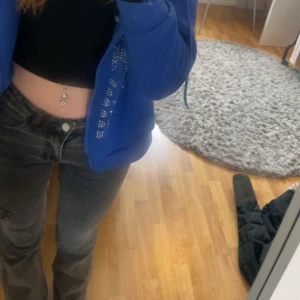 Mörkgrå bootcut jeans - Säljer ett par mörkgrå jeans med bootcut passform och låg midja. Jeansen har klassisk femficksdesign och knappstängning framtill. Perfekta för dig som gillar en avslappnad och trendig stil.