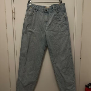 Dime  - Säljer ett par ljusblå jeans från Dime med broderad logga på både fram- och baksida. Klassisk femficksmodell med raka ben och snygga detaljer som gul etikett och specialdesignade knappar. Jeansen har hög midja och är tillverkade i slitstark denim.