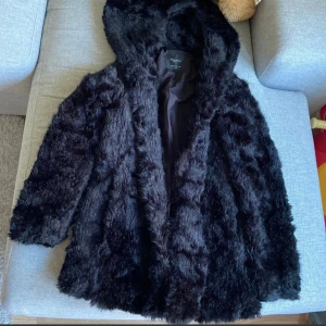Zara svart jacka, st.XS,fuskpäls - Svart, fluffig mjuk skön jacka fuskpäls från Zara. Knappt använd.Mycket bra skick Jackan har en huva och knäpps med knappar.hämtas i norsborg botkyrka eller fraktas skynda fynda .storlek Xs passar även Storlek S tror jag.