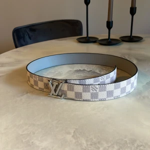 Louis bälte - Säljer nu detta bälte som är i färgerna vitt och svart med rutigt mönster och med deras silvriga logga // Längd: 100 cm // skick 8/10 // skriv i dm vid frågor eller funderingar!!!