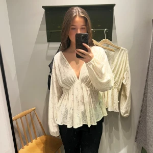 Vit spetsblus med v-ringning från Vila - Superfin vit blus från Vila med djup v-ringning och långa ärmar. Blusen har ett spetsigt mönster, markerad midja och lätt volang nedtill. Luftigt material och snygg passform som ger en romantisk vibe.