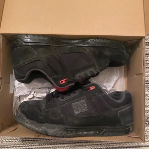 Svarta DC sneakers med röda detaljer - Säljer ett par svarta DC sneakers som är perfekta inför vintern då dem är varma och bekväma (dma mig för bättre bilder på lite skador här och där eller andra frågor)
