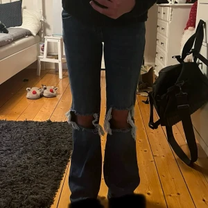 Blå bootcut jeans med slitna knän  - Mörkblå bootcut jeans från 157 med snygga slitningar över knäna. Klassisk femficksmodell med dubbla knappar i midjan och raka bakfickor. Jeansen har en lite utsvängd passform nertill och är tillverkade i jeansmaterial.