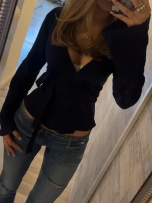 Mörkblå omlottopp  - Säljer en mörkblå omlottopp från Gina Tricot i storlek S. Toppen har långärmade ärmar, v-ringad hals och knyt i midjan för en snygg siluett💞