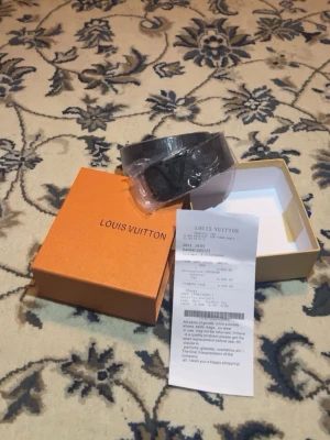 Louis Vuitton svart skinnbälte - Säljer ett svart Louis Vuitton-bälte i skinn med klassiskt LV-spänne. Bältet kommer i original orange box och har en stilren design som passar till det mesta. Bredden är 4 cm och längden 120 cm. Perfekt accessoar för dig som vill ha något exklusivt och tidlöst. Priset kan diskuteras.