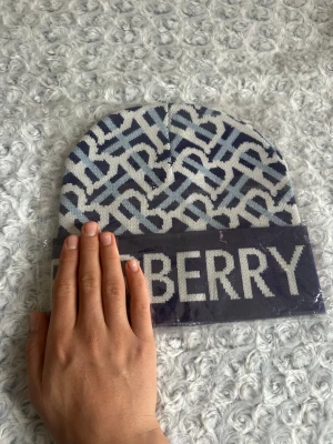  blåvit mönstrad mössa - Snygg mössa med blå och vita färger samt ett grafiskt mönster över hela ytan. Upptill har mössan ett stilrent mönster med signaturstil och nedtill en bred uppvikt kant med logotyp. Perfekt för dig som gillar exklusiva accessoarer.